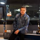 Jeremy Renner on set of Rennervations, a bus behind him and some power tools to one side (Credit: Disney+)