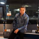 Jeremy Renner on set of Rennervations, a bus behind him and some power tools to one side (Credit: Disney+)