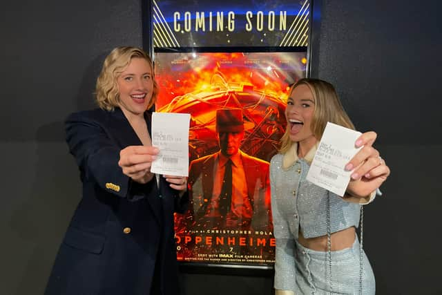 Barbie director Greta Gerwig and star Margot Robbie pose in front of the Oppenheimer poster 