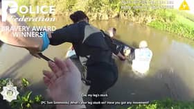 Woman is rescued from neck-level flood water in submerged car.