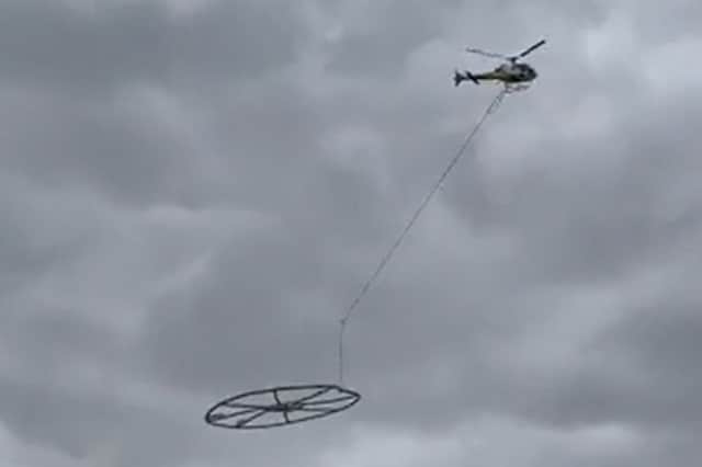 Helicopter carrying large metal circle.
