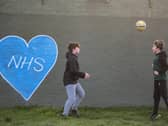 Children play football in the park next to graffiti in support of the NHS. Photo:Justin Setterfield