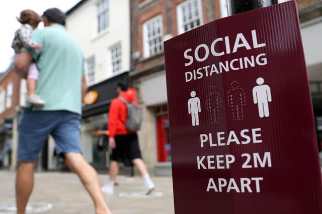 People walk past a social distancing sign, ahead of the re-opening of non-essential retailers in England on June 15. Photo: PA