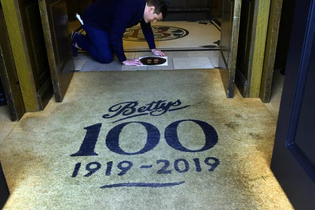 Robin Cox Visual Merchandising Manager at Bettys fixing the 2m signs to the floor at the entrance to the Harrogate shop. Picture: Gary Longbottom