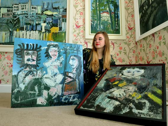 Scarlett Stewart, a curator at Harrogate's 108 Fine Art, with an example of paintings by Joash Woodrow at a previous exhibition at the gallery.