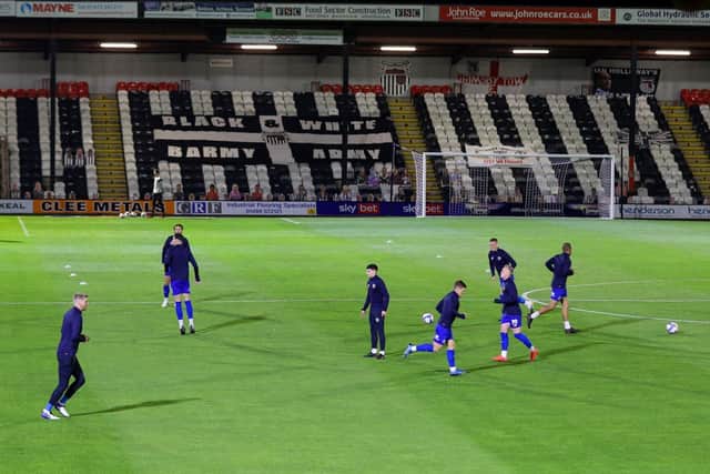 The Harrogate players warm-up in front of a near-empty Blundell Park.