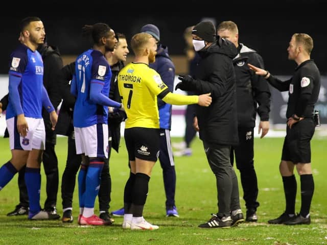 Players and staff from both sides confront the match officials following the decision to abandon Harrogate Town's clash with Carlisle United. Pictures: Matt Kirkham