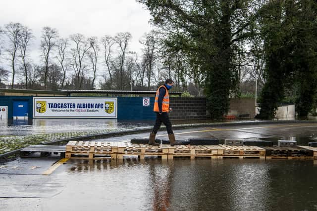 21 January 2021.....  A worker from the John Smith's Brewery walks on pallets over tghe flood water engulfing Tadcaster Albion's football ground. Picture Tony Johnson