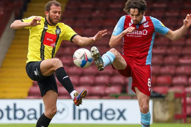 Harrogate Town striker Aaron Martin challenges Scunthorpe United's Alex Gilliead.