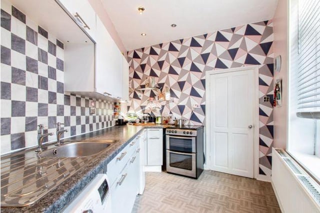 The fitted kitchen is modern and sleek, and the current owners have added a pop of colour with a patterned wallpaper.