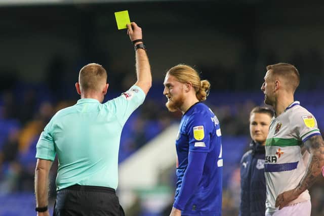Referee Darren Handley shows Harrogate Town striker Luke Armstrong a yellow card.