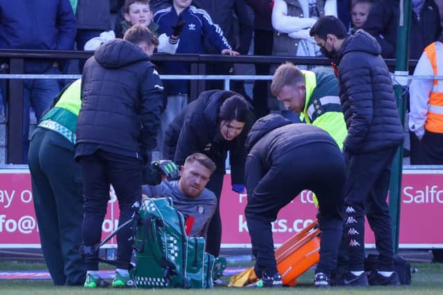 Mark Oxley receives treatment shortly before being substituted due an injury sustained in the build-up to Salford's opening goal.