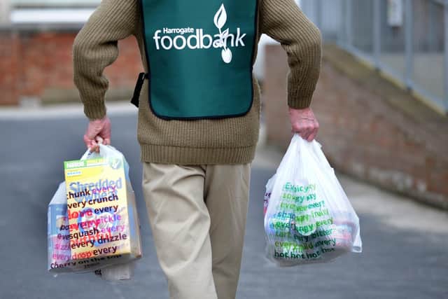 A volunteer at the Harrogate Food Bank at Mowbray Community Church in  Harrogate carrying some bags filled with food.