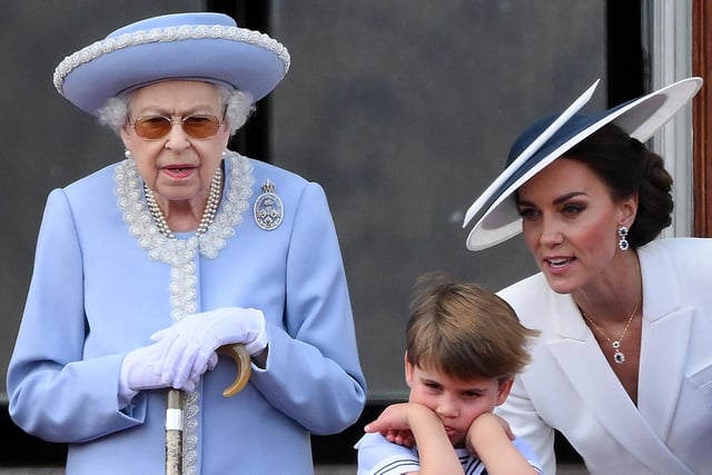 Catherine, Duchess of Cambridge, talks to Prince Louis of Cambridge as they stand with Queen Elizabeth II, to watch a special flypast from the Buckingham Palace balcony.