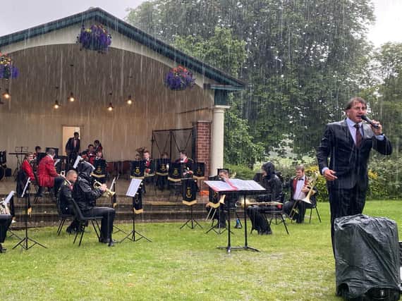 Tewit Youth Band and its Musical Director, Martin Hall bravely play on in a thunderstorm at the Valley Gardens in Harrogate.