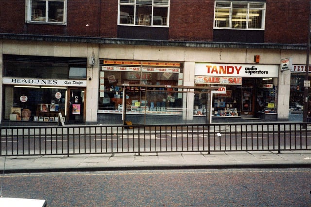 Shops on south side of Eastgate in March 1984. From left, is Headlines Hair Design, Tandys Hi-Fi and audio superstore, and just visible on the right, No 28 Peter Maturi Cutlery specialists.