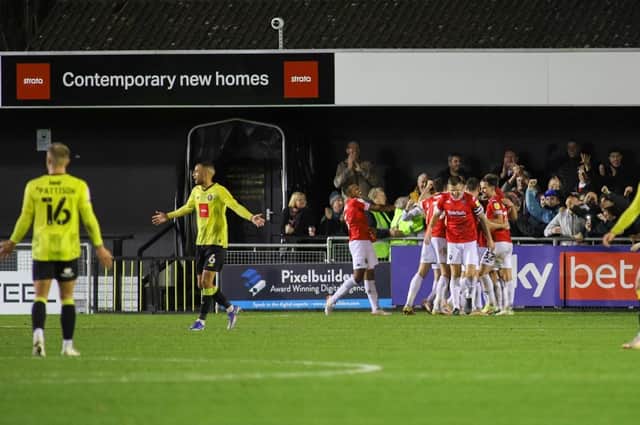 Harrogate Town players hold an inquest out on the field as Salford City celebrate taking a 2-0 lead at the EnviroVent Stadium. Pictures: Matt Kirkham