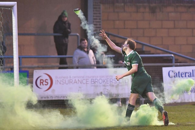 A Lakenheath striker throws a flare off the pitch