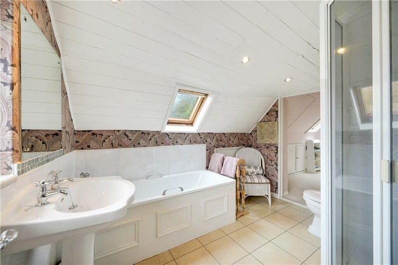 A bathroom with white suite includes a walk-in shower unit.