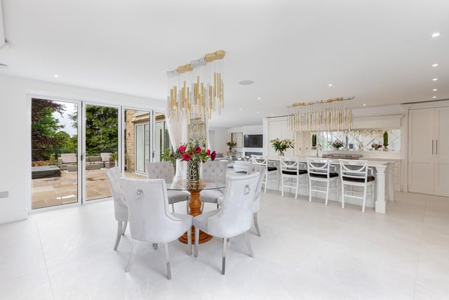 This showcase kitchen with living and dining areas has bi-fold doors to a large patio area.