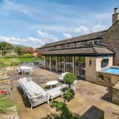 The house has lawned and landscaped gardens of over an acre, with seating areas, and a tennis court.