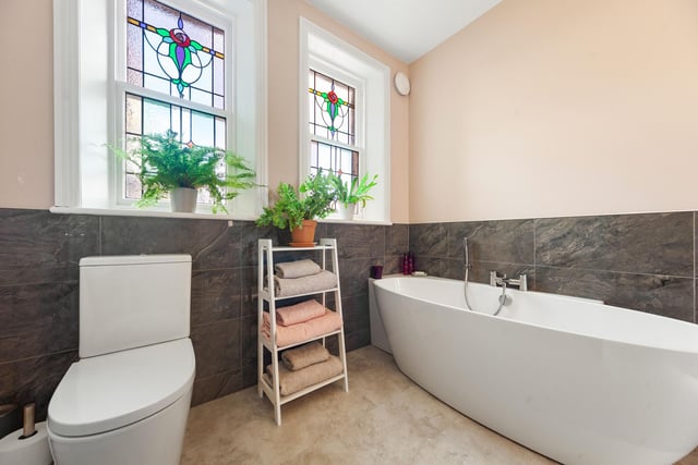 A bathroom with feature stained glass windows and freestanding bath tub.