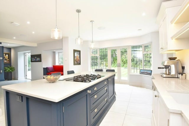The bespoke kitchen with central island has integrated appliances, with doors leading out tot he garden.