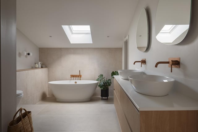 A contemporary bathroom with twin washbasins and a freestanding bath.