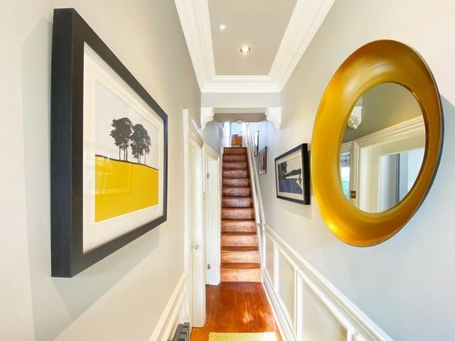 A hallway with panelled walls, and staircase up.