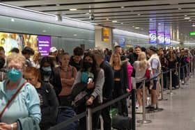 Travellers wait in a long queue to pass through the security check. (Photo by Carl Court/Getty Images)