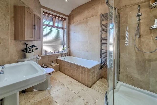 A fully tiled bathroom has both bath and shower unit within its suite.