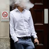 A smoker is engulfed by vapours as he smokes an electronic vaping machine.