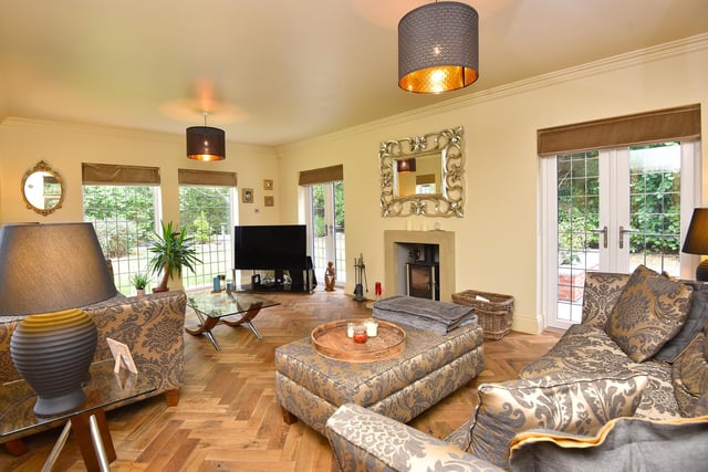 This stylish sitting room has parquet flooring, with a feature fireplace and wood-burning stove. Patio doors lead outside.