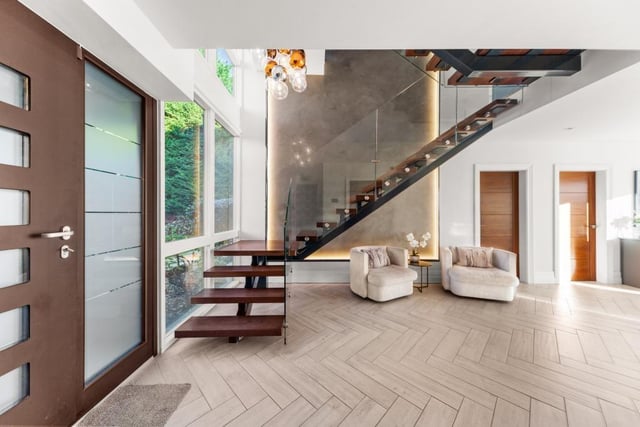 A welcoming hallway has a feature angular staircase with white oak treads and glass balustrade.