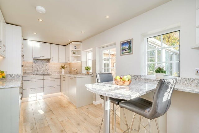 A modern kitchen has granite worktops and integrated appliances.