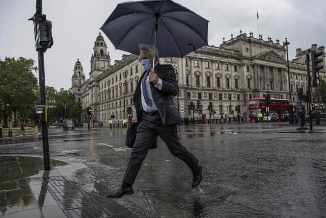 A man jumps over a puddle during a thunderstorm. (Pic credit: Dan Kitwood / Getty Images)