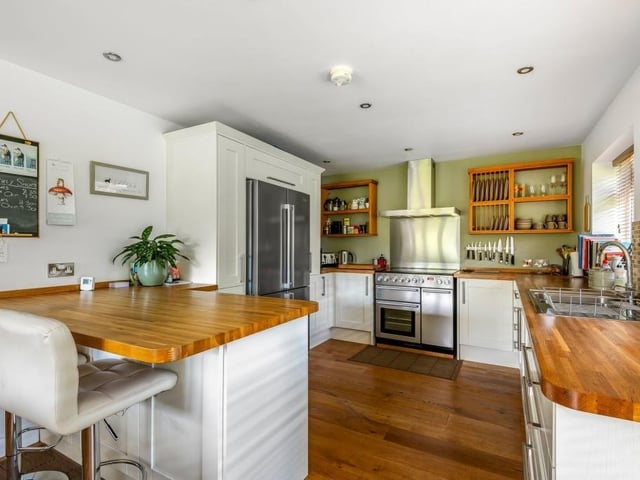An open plan living and dining kitchen with oak flooring is fitted with units and oak worktops