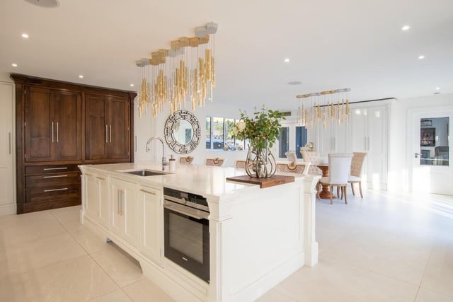 The luxurious living kitchen with walnut cabinets and marble worktops has a feature central island.