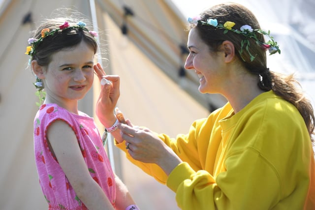 Leanne Walsh helping her daughter Esme Walsh (aged six) get into the festival spirit by putting glitter on her face