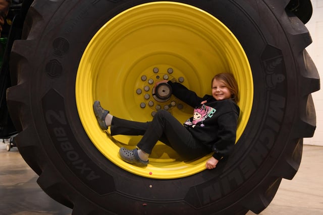 Eight-year-old Harriet Randall sits in the wheel of a John Deere tractor