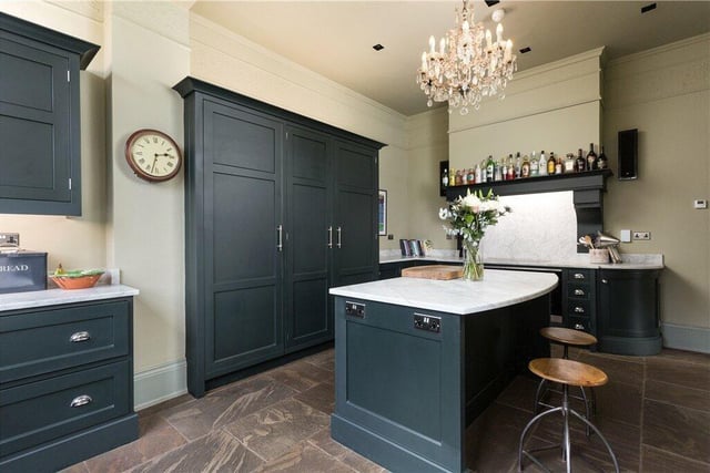 A bespoke kitchen by Jeremy Wood Interiors is separated from the dining room by a double-sided multi-fuel stove.
