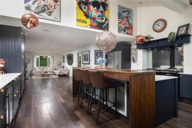 The deluxe open plan living kitchen has a Scandinavian dual fuel stove at its centre, an island unit with breakfast bar, and many fitted appliances, plus an AGA.