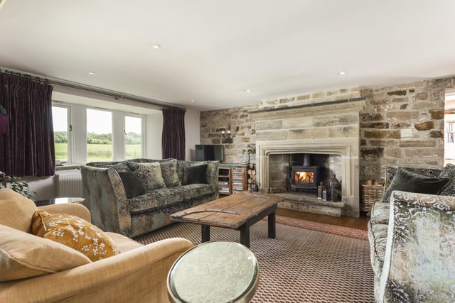 A stove within the stone fireplace adds cosiness to this comfortable sitting room with country views.