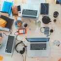 People sitting with assorted laptops and digital devices at a table.