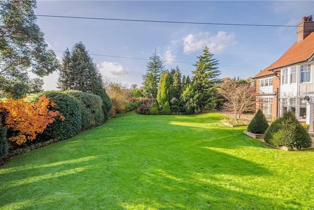 Lawned gardens to three sides of the house are bordered by high hedges, ensuring privacy.