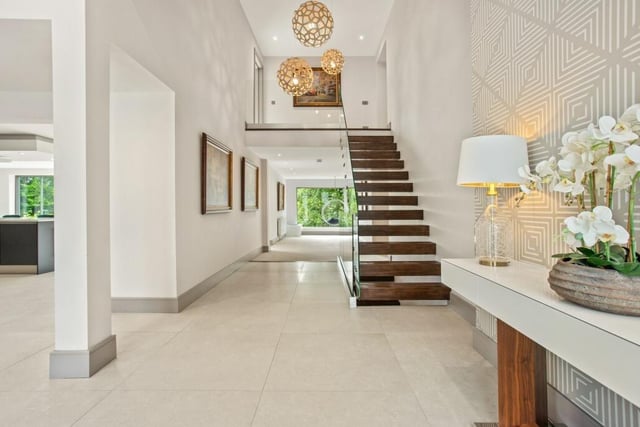 The hallway with porcelain tile flooring features a 'floating' staircase.