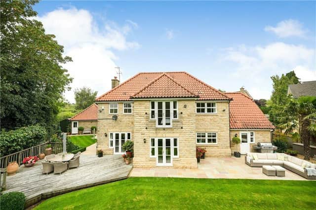 A rear view of the property and its gardens, with seating areas that have extensive views.