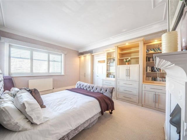 A double bedroom with a fireplace and fitted furniture.