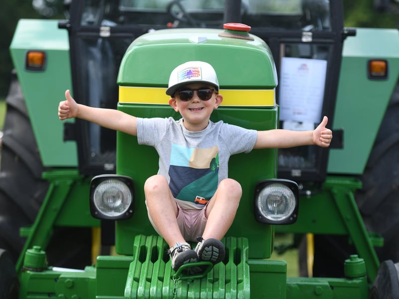Archie Davies (aged five) sitting on the front of a tractor in the sunshine at Newby Hall