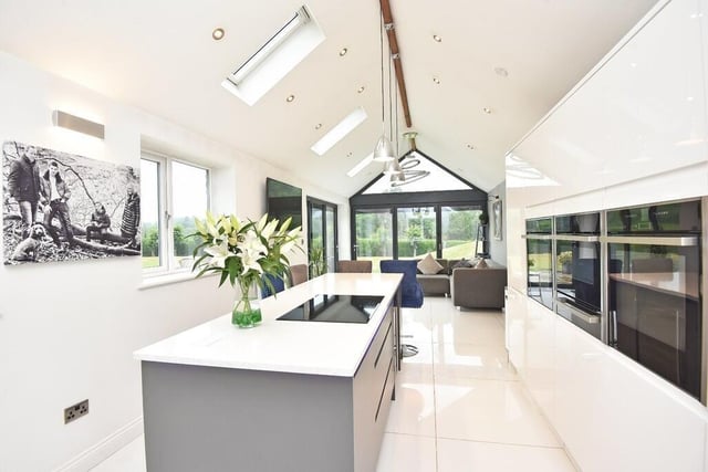 The sleek, high spec kitchen has an island with breakfast bar, and integrated appliances.